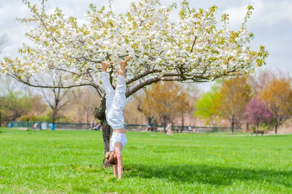 Femeia practică yoga, face exerciții Salamba Sirsasana, stând în picioare în poziție de mână lângă copac — Fotografie, imagine de stoc