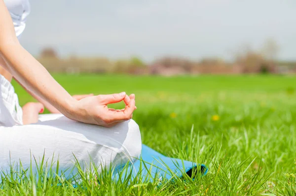 Donna sta meditando seduto in Lotus posa su erba al parco . — Foto Stock