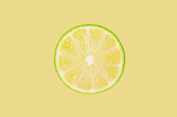 Lime slice on pastel yellow background — Stock Photo, Image