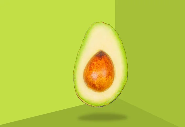Avocado levitate in air on green background. Concept of vegetable levitation. — Stock Photo, Image