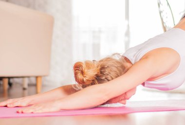 Kadın fitness mat üzerinde germe yapıyor. Evde balasana yoga yapan kadın, 