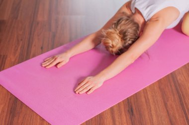 Kadın fitness mat üzerinde germe yapıyor. Evde balasana yoga yapan kadın, 