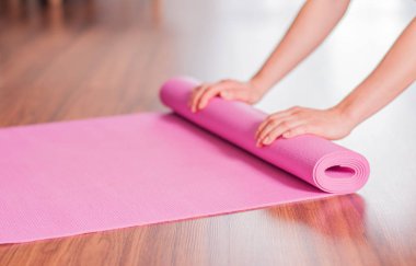 Eller kadın evde egzersiz sonrası yoga veya fitness mat katlama