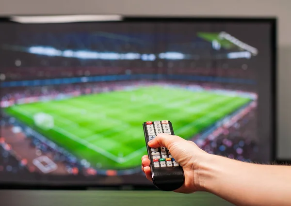 Hombre viendo el partido de fútbol en la televisión, el control remoto en la mano . — Foto de Stock