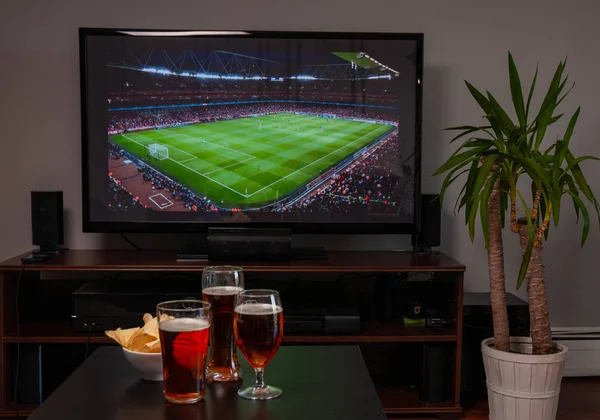 テレビの前でビールグラスとチップ、自宅でサッカー — ストック写真