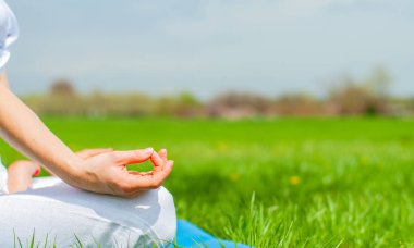 Kadın Lotus 'ta meditasyon yapıyor. Parktaki çimlerde poz veriyor.. 