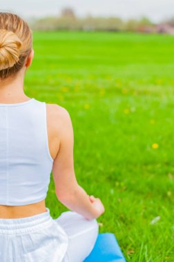 Kadın Lotus 'ta meditasyon yapıyor. Parktaki çimlerde poz veriyor.. 