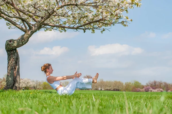 Femeia frumoasă practică yoga, făcând Paripurna Navasana pozează, pozează lângă copac — Fotografie, imagine de stoc