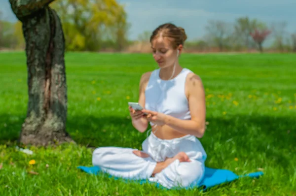 O femeie frumoasă practică yoga stând în Lotus pozând lângă copacul înflorit — Fotografie, imagine de stoc