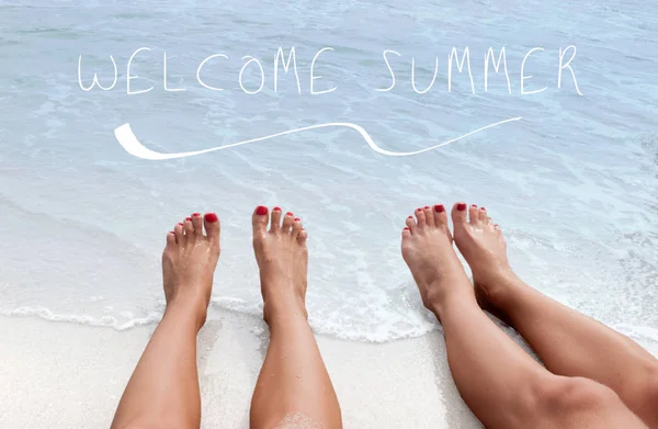 Fond de la mer avec lettrage bienvenue été. Jambes féminines sur la plage . — Photo