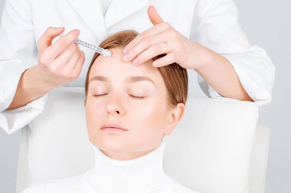 A nő injekciót kap a homlokába. Öregedés elleni kezelés és arcfelvarrás. Arcfelvarrás injekció a nő arcába. — Stock Fotó