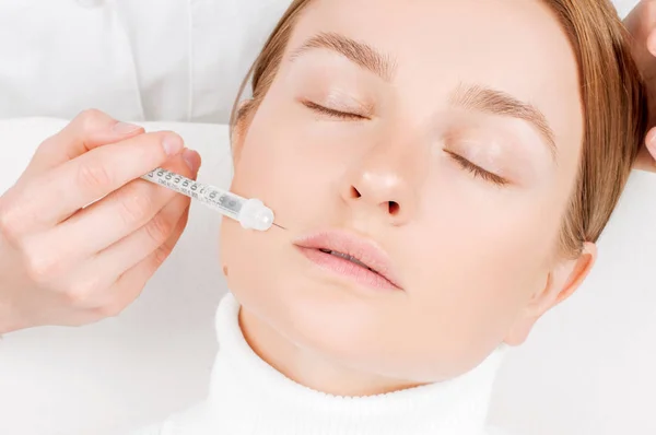 Hermosa mujer recibiendo inyección de relleno en los labios. Tratamiento antienvejecimiento y lifting facial . — Foto de Stock