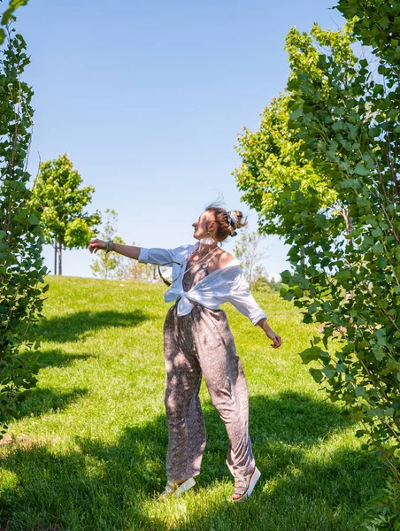 晴れた日に自由を楽しむ美しいボーホスタイルの女の子。緑の草の上にジャンプ陽気な女性 — ストック写真