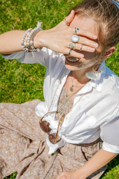 Belle femme de style boho avec beaucoup d'accessoires, bagues et bracelets sur herbe verte . — Photo