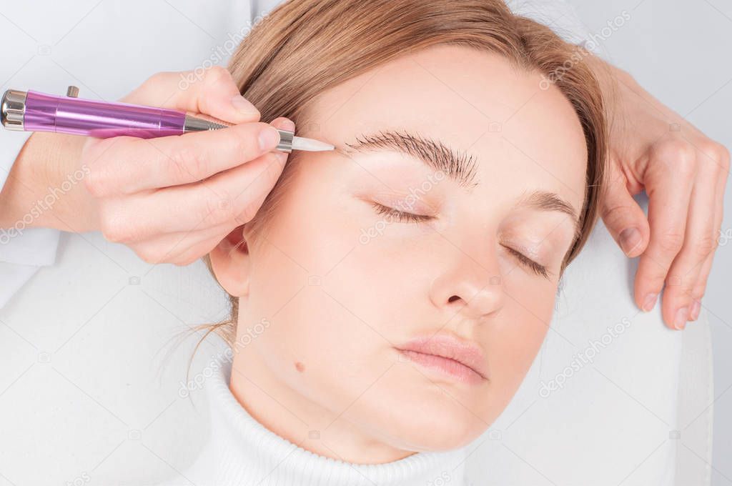 Microblading eyebrows. Attractive woman getting facial care and permanent makeup. 