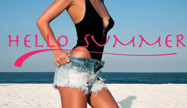 こんにちは夏の文字と海の背景。ビーチで黒い水着とジーンズのショートパンツの美しい女性. — ストック写真
