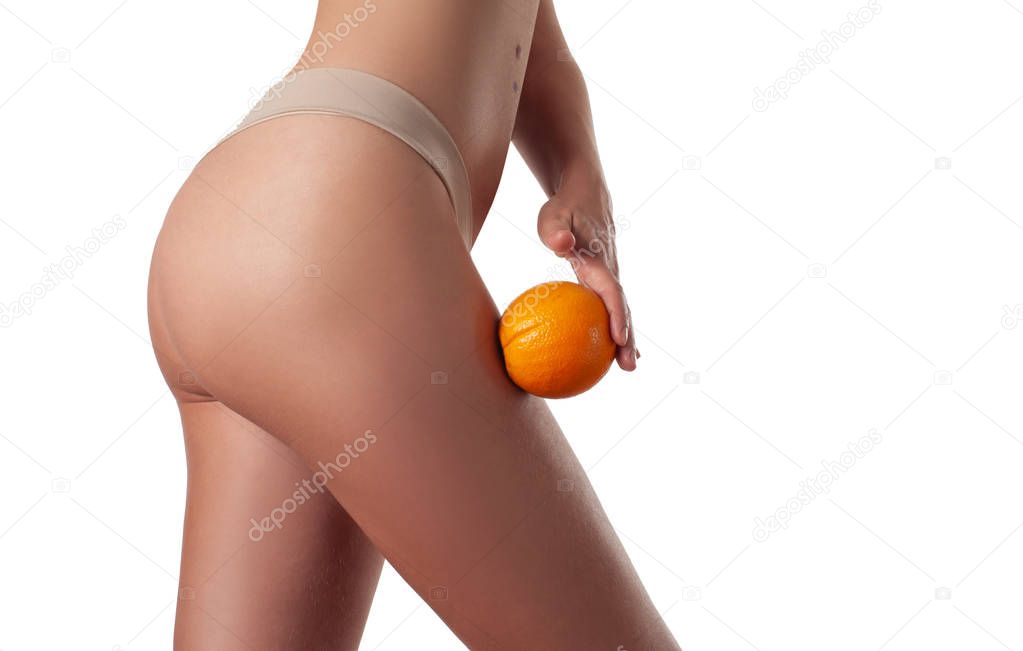 Body care and anti cellulite massage. Perfect female buttocks without cellulite in panties. Beautiful woman's butt in underwear with orange.