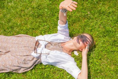 Aksesuarları bir sürü güzel boho tarzı kadın yeşil çim üzerinde yatıyor. Mutlu mometn