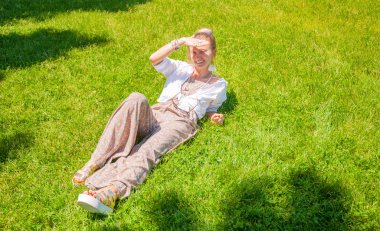 Aksesuarları ile Güzel boho tarzı kadın parkta çim üzerinde yaz güneşli gün tadını çıkarıyor.
