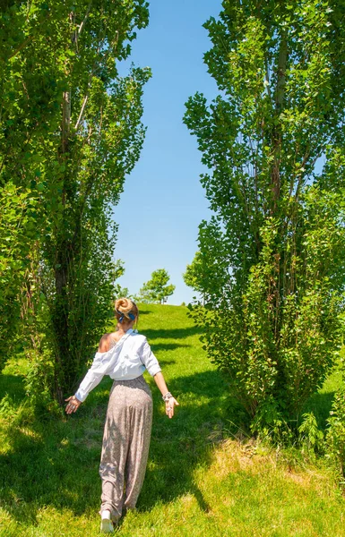 Piękna kobieta w stylu boho jest chodzenie na trawie i cieszyć się latem w parku. — Zdjęcie stockowe