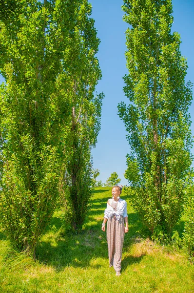 Piękna kobieta w stylu boho jest chodzenie na trawie i cieszyć się latem w parku. — Zdjęcie stockowe