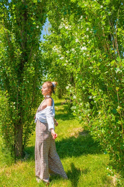 Frumoasă femeie în stil boho în salopetă la modă, bucurându-se de timpul de vară în parc — Fotografie, imagine de stoc