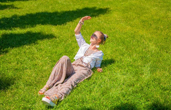 Frumoasa femeie în stil boho cu accesorii se bucură de o zi însorită de vară pe iarbă în parc . — Fotografie, imagine de stoc