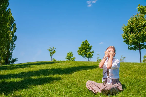 O femeie frumoasa isi acopera mainile pe iarba. Frumoasa femeie în stil boho cu accesorii se bucură de o zi însorită de vară în parc . — Fotografie, imagine de stoc