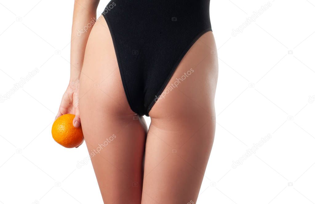 Body care and anti cellulite massage. Perfect female buttocks without cellulite. Beautiful woman's butt in underwear with orange.