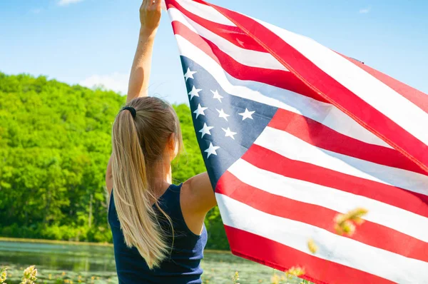 Kobieta trzyma amerykańską flagę na zewnątrz. Stany Zjednoczone świętować 4 lipca Dzień Niepodległości. — Zdjęcie stockowe