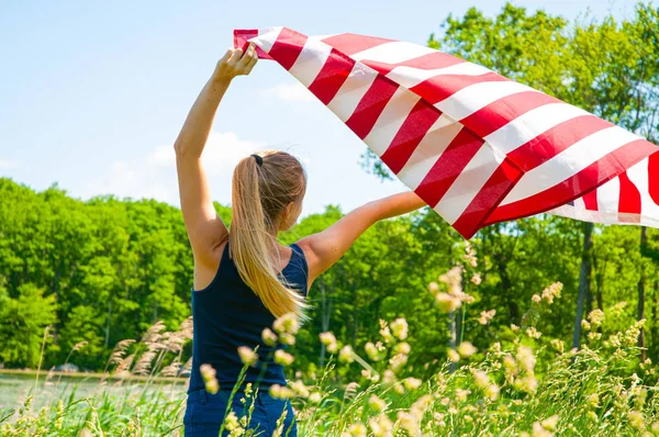 屋外でアメリカ国旗を持つ女性。米国は7月の独立記念日の4日を祝う. — ストック写真