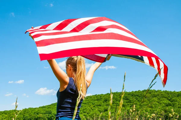 Jovem segurando bandeira americana no fundo do céu azul . — Fotografia de Stock