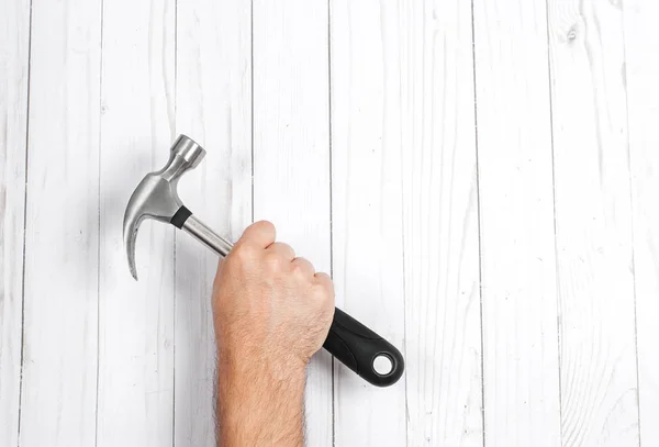 Herramienta. La mano sostiene el martillo sobre un fondo de madera  . —  Fotos de Stock