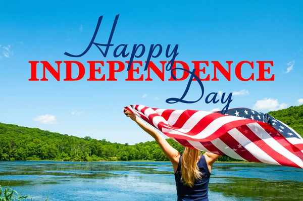 해피 독립 기념일, 7 월 4 일. 호수 배경에 미국 국기를 들고 있는 젊은 여성. — 스톡 사진