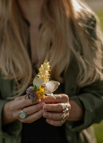 Piękna kobieta z długim włosami trzyma kwiat. Ręce z pierścieniami stylowe akcesoria Boho. Brak fokusu — Zdjęcie stockowe