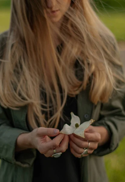Piękna kobieta z długim włosami trzyma kwiat. Ręce z pierścieniami stylowe akcesoria Boho. Brak fokusu — Zdjęcie stockowe