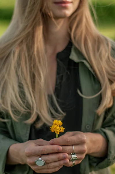 Beautiful woman with long hair holding flower. Hands with rings stylish boho accessories. No focus