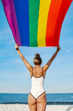Sahilde LGBT bayrağı tutan lezbiyen bir kadın. Gay Gökkuşağı bayrağı. Lgbt topluluğu