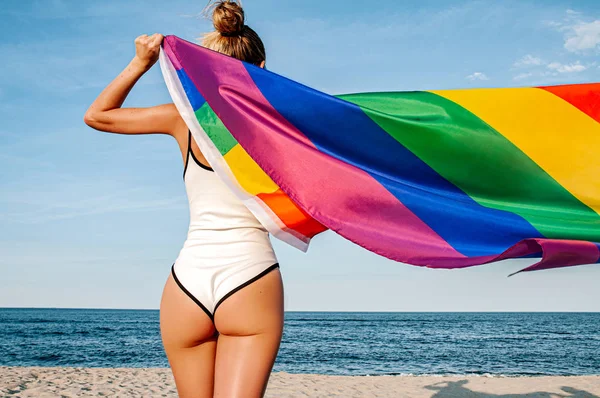 Mujer lesbiana con bandera LGBT en la playa. Bandera Gay Rainbow. Comunidad LGBT — Foto de Stock