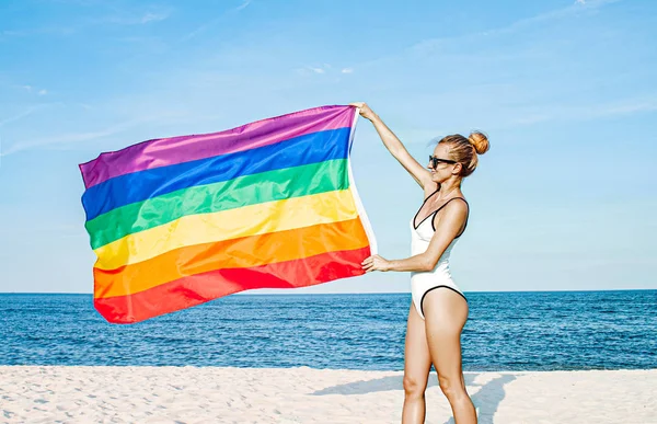 Mujer lesbiana con bandera LGBT en la playa. Bandera Gay Rainbow. Comunidad LGBT — Foto de Stock