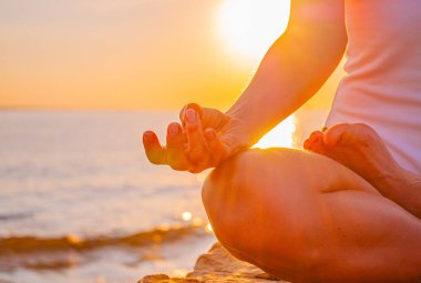 Kadın gün doğumunda Lotus poz oturan yoga yapıyor. Sahilde gün batımında meditasyon kadın silueti