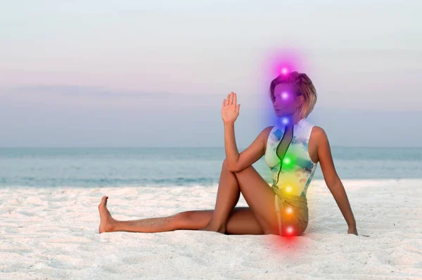 La mujer está meditando con siete chakras brillantes en la playa. Hermosa mujer está practicando yoga al atardecer . —  Fotos de Stock