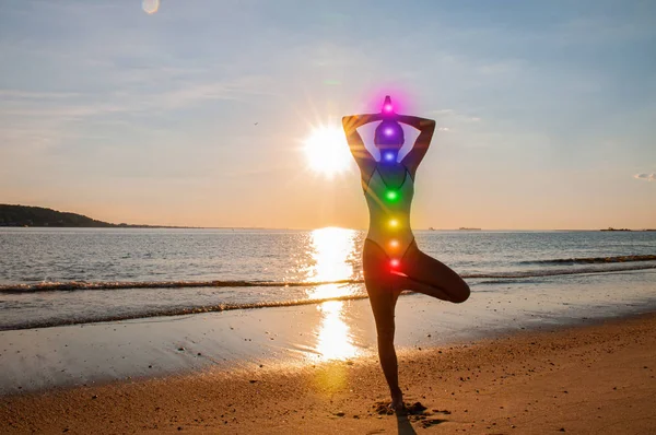 Silhouette kvinna yoga på stranden vid solnedgången. Kvinnan tränar yoga vid solnedgången på havskusten. — Stockfoto
