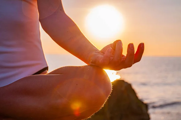 Mulher está praticando ioga sentado em pose de lótus ao nascer do sol. Silhueta de mulher meditando ao pôr do sol na praia — Fotografia de Stock