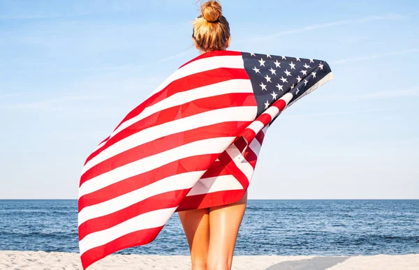 Mulher patriótica bonita com bandeira americana na praia. Dia da independência dos EUA, 4 de julho. Conceito de liberdade . — Fotografia de Stock