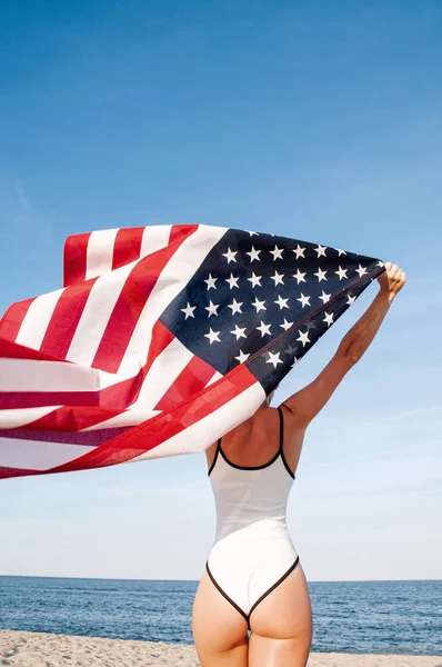 Piękna patriotyczna kobieta posiadająca amerykańską flagę na plaży. USA Dzień Niepodległości, 4 lipca. Koncepcja wolności. — Zdjęcie stockowe