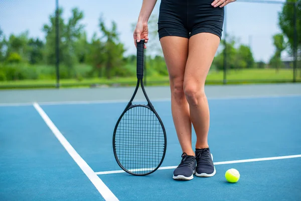 テニスコートにテニスラケットを持つ美しい女性の足 — ストック写真