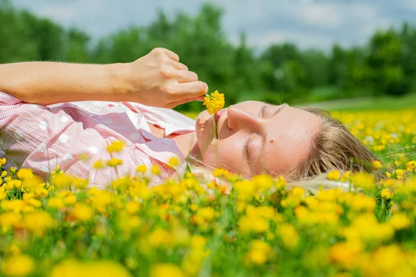 O femeie fericită întinsă pe câmp în iarbă cu flori galbene în aer liber. Bucură-te de natură. Alergie gratuită . — Fotografie, imagine de stoc