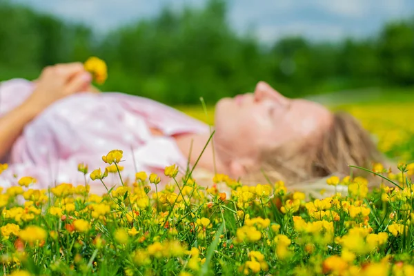 O femeie fericită întinsă pe câmp în iarbă cu flori galbene în aer liber. Bucură-te de natură. Alergie gratuită . — Fotografie, imagine de stoc