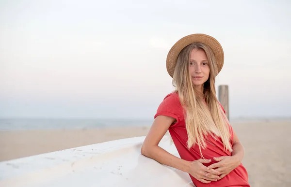 Beautiful woman with long hair wear straw hat on the beach near wooden boat. — Stock Photo, Image